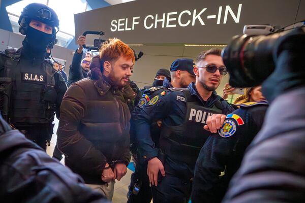 Mohamed Amra, nicknamed ''The Fly", is escorted by armed police officers at the Henri Coanda international airport in Otopeni, Romania, Tuesday, Feb. 25, 2025, before being extradited to France. (AP Photo/Vadim Ghirda)