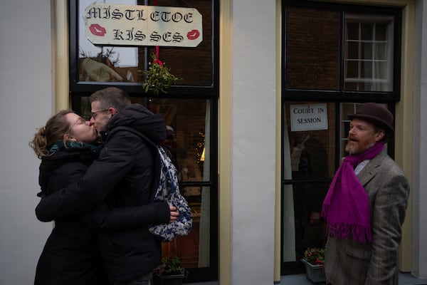 A couple of spectators kiss under mistletoe during a Dickens Festival, in Deventer, Netherlands, Saturday, Dec. 14, 2024. (AP Photo/Peter Dejong)