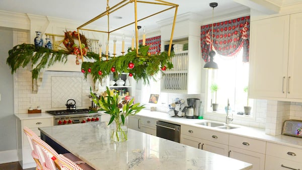 The metal chandelier over the island, from Circa Lighting, is draped with cedar branches from the backyard for a wintery touch. The island is topped with marble countertops from Atlanta Kitchens. For the remodel, the homeowners worked with designer Robin Pittman, Pearl Custom Cabinets and contractor Heriberto Lopez.