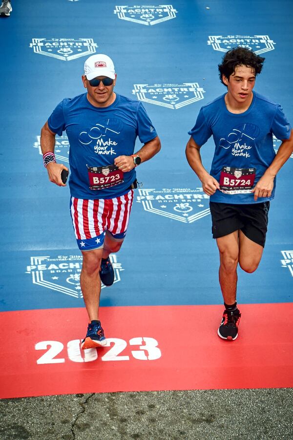 AJC publisher and president Andrew Morse and his son, Holden, cross the finish line at the 2023 AJC Peachtree Road Race. Courtesy of Andrew Morse