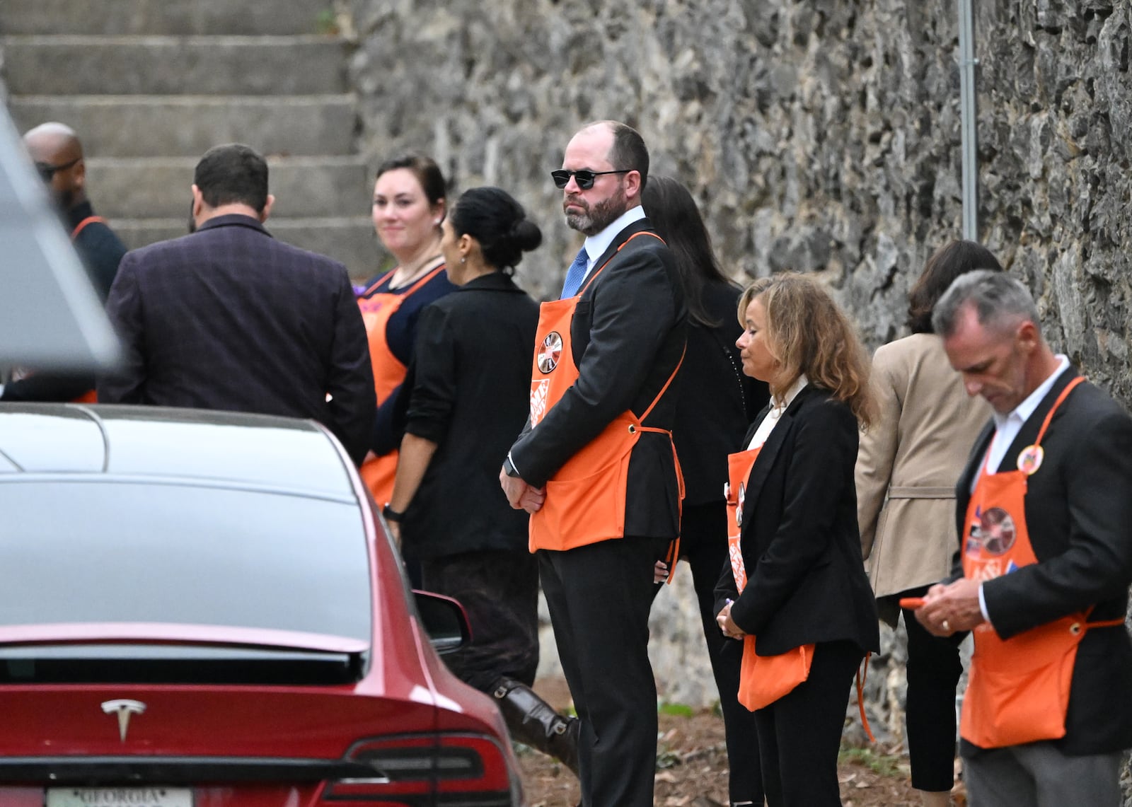 People wearing Home Depot apron greet guests arriving  for the funeral service of Bernie Marcus at The Temple, Thursday, November 7, 2024, in Atlanta. Bernie Marcus died Monday at his Boca Raton home. He was 95. His funeral in Atlanta is Thursday afternoon. One of Georgia’s most prominent philanthropists and a major donor nationally, Marcus found that methodically giving away his vast fortune was immensely satisfying. (Hyosub Shin / AJC)