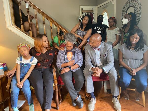 Matthew Williams' mother holds up his photo as she is consoled by family members in her living room. Williams was killed during an encounter with police at his DeKalb County condo.