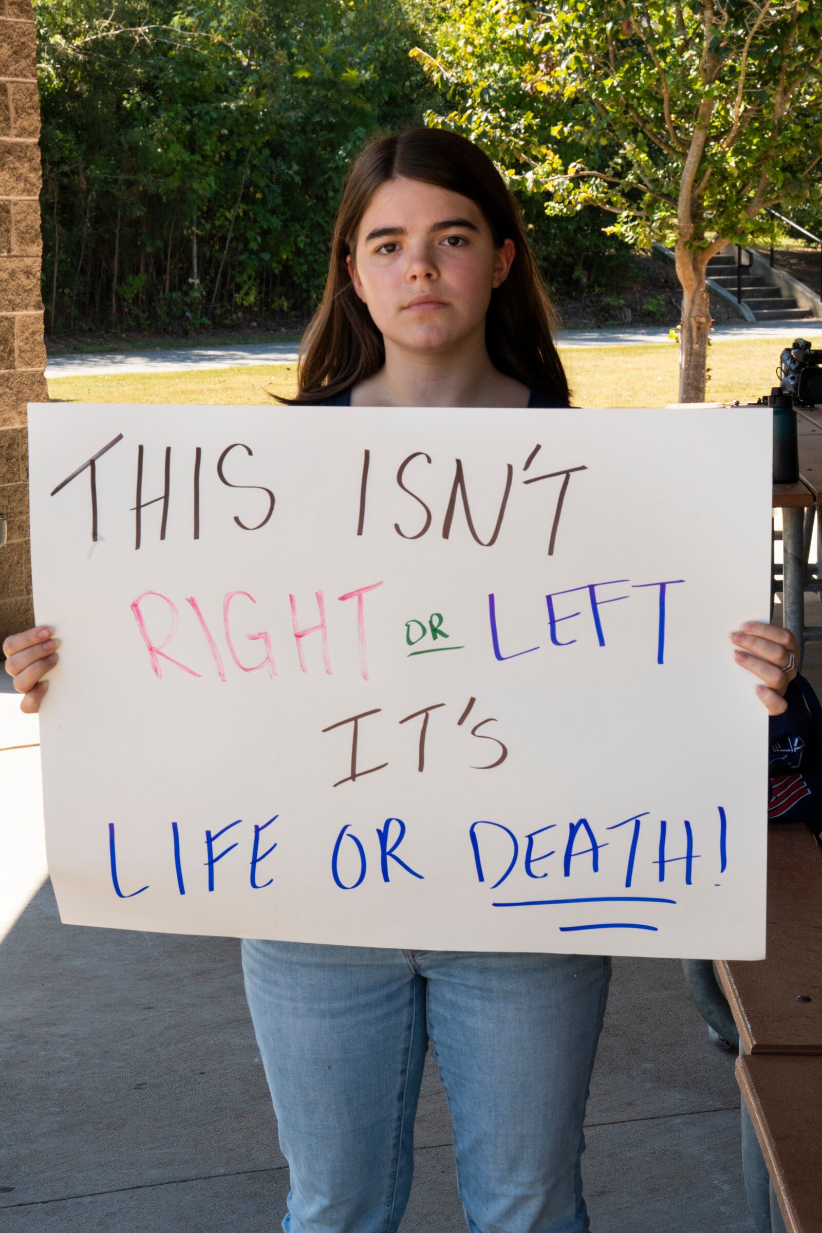 Celeste Rosellil, a 10th grade student from The Westminster Schools, poses with a sign during a rally at J.B. Williams Park on Friday Sept. 20, 2024. (Olivia Bowdoin for the AJC)