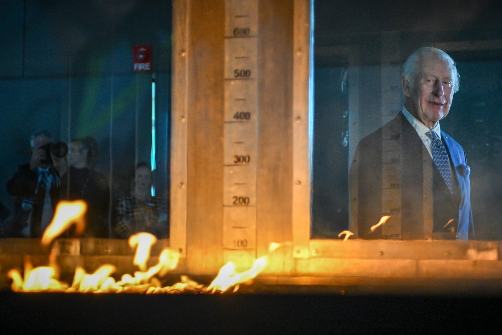 Britain's King Charles III listens to research scientist Dr. Matt Plucinski describe the "Pyrotron" combustion wind tunnel during a visit to the CSIRO National Bushfire Behaviour Research Laboratory in Canberra, Monday, Oct. 21, 2024. (AP Photo/Tracey Nearmy, Pool)