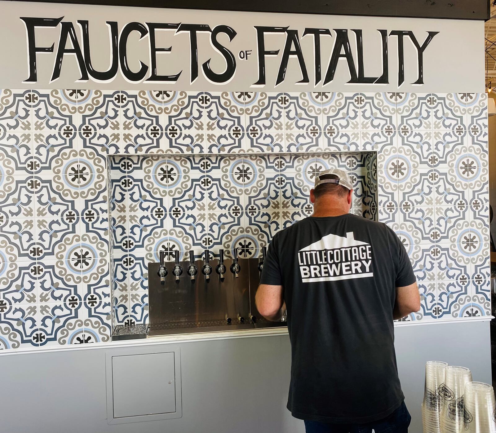 Brewer Jon Shari works the taps behind the bar at Little Cottage Brewery in Avondale Estates. (Bob Townsend for The Atlanta Journal-Constitution)