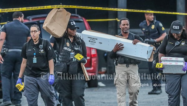 An Atlanta police investigator carries a rifle evidence box out of the Onyx Atlanta strip club after a shooting that wounded two people Tuesday morning.