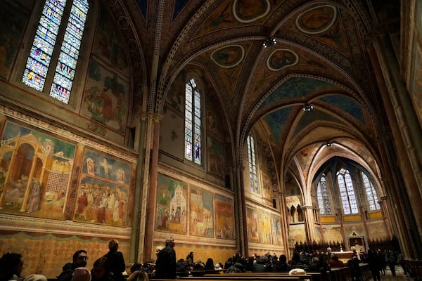 People visit the central nave of St. Francis Basilica in Assisi, Italy with frescoes of Giotto, Saturday, March 1, 2025. (AP Photo/Gregorio Borgia)