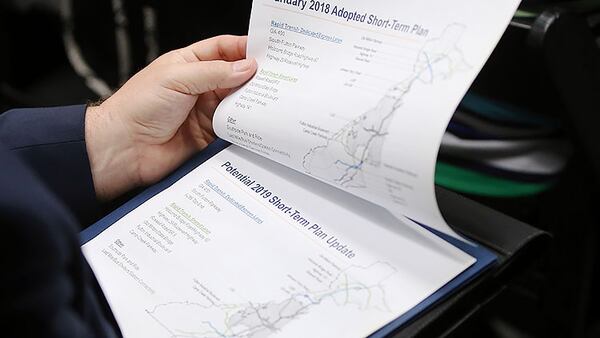 An attendee holds the agenda at the Fulton County Government Center to discuss funding a transit plan that could include rapid bus transit along I-285.