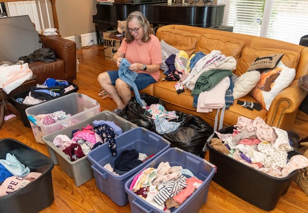 Fran Cameron sorts clothing by size and gender in her East Cobb home. She and her husband, Doug, have turned their garage into a makeshift thrift store. PHIL SKINNER FOR THE ATLANTA JOURNAL-CONSTITUTION