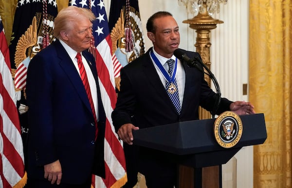 President Donald listens as Tiger Woods speaks during reception for Black History Month in the East Room of the White House Thursday, Feb. 20, 2025. (Pool via AP)