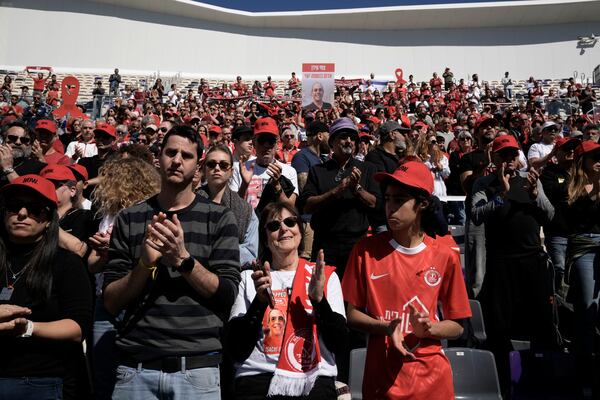 Dvora Idan, center, and her family applaud at a public memorial ceremony for her son, slain hostage Tsachi Idan, a fan of Hapoel Tel Aviv F.C., who was killed in Hamas captivity in the Gaza Strip, at Bloomfield Stadium in Tel Aviv, Israel, Friday, Feb. 28, 2025. (AP Photo/Leo Correa)