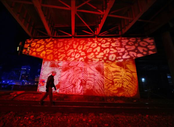 Artists have turned a Martin Luther King Jr. Drive bridge support into a work of projected art in the Gulch as part of the Heartbeat ATL art installation on Monday, Jan. 31, 2022, in Atlanta. People have described the area to be a ”hole in the heart" of Atlanta for years, a boring expanse of parking lots. Centennial Yards, the folks building a work-play-shop area there, teamed with some local artists to create a heartbeat-based light installation that can be triggered by a website you can got to by scanning QR codes set up around the area. Curtis Compton / Curtis.Compton@ajc.com