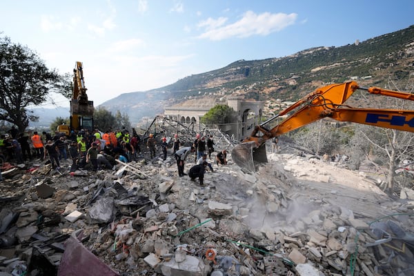 Rescue workers use excavators to remove the rubble of a destroyed house hit in an Israeli airstrike, as they search for victims in Aalmat village, northern Lebanon, Sunday, Nov. 10, 2024. (AP Photo/Hassan Ammar)