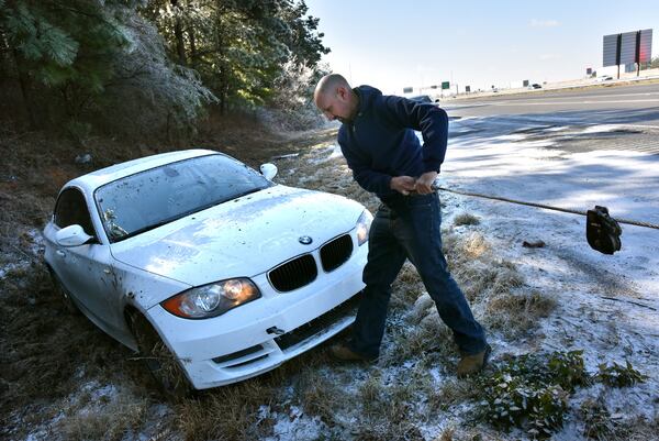 January 7, 2017 Lawrenceville - Gabriel Suarez with J & S Towing Service prepares the vehicle for towing from a difficult position alongside I-85 northbound near Old Peachtree Road exit in Gwinnett County on Saturday, January 7, 2017. Snow fell in parts of Georgia on Friday night, but much of metro Atlanta got very little or no snow at all. Still, many areas Saturday are facing icy conditions on the roads. There is a danger of slick conditions on bridges and overpasses, Channel 2 Action News meteorologist Karen Minton said.  HYOSUB SHIN / HSHIN@AJC.COM