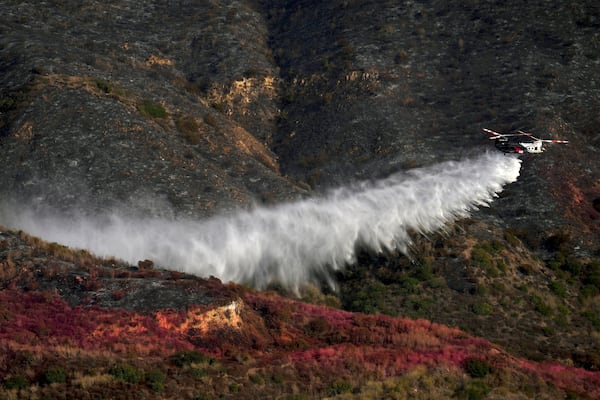 Water is dropped onto the Franklin Fire by helicopter, Wednesday, Dec. 11, 2024, in Malibu, Calif. (AP Photo/Eric Thayer)