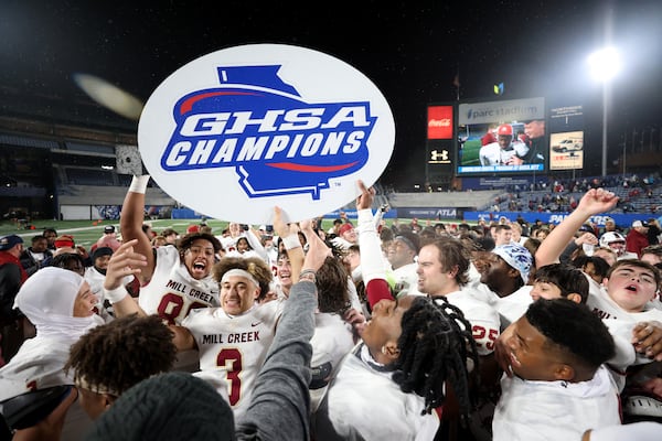 Mill Creek’s Nick Maxey (88), Trajen Green (3) and teammates host the GHSA Champions sign after their 70-35 win against Carrollton in the GHSA Class 7A finals, at Center Parc Stadium, Saturday, December 10, 2022, in Atlanta. (Jason Getz / Jason.Getz@ajc.com)