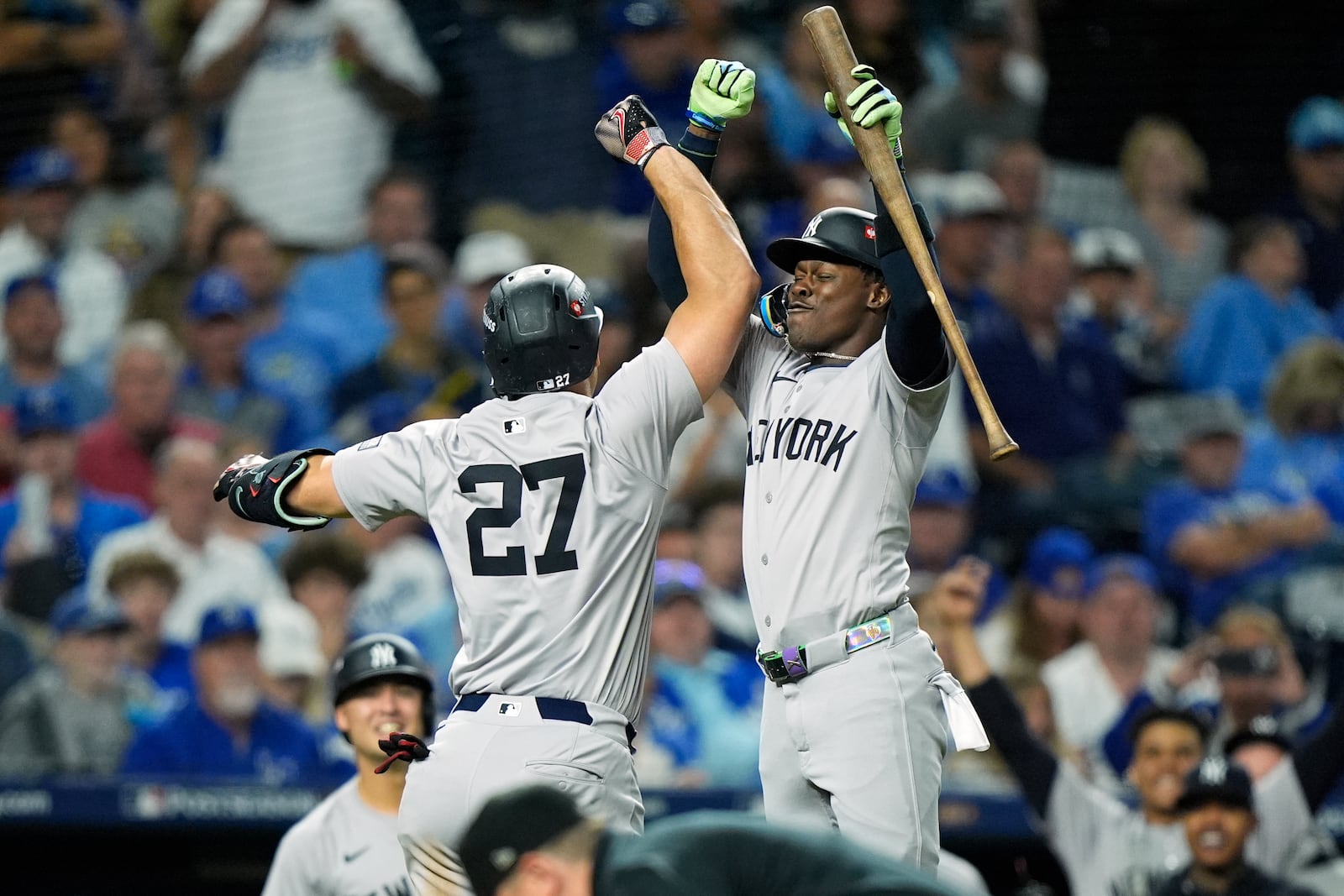 New York Yankees' Giancarlo Stanton (27) is congratulated by teammate Jazz Chisholm Jr. after hitting a solo home run during the eighth inning in Game 3 of an American League Division baseball playoff series against the Kansas City Royals Wednesday, Oct. 9, 2024, in Kansas City, Mo. (AP Photo/Charlie Riedel)