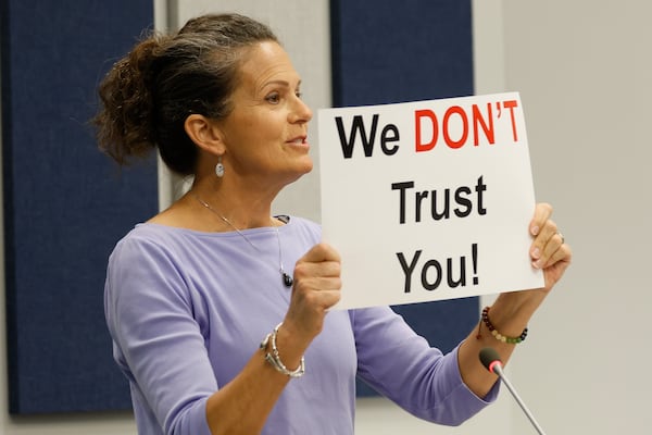 Christine Rozman shows a sign that reads "We don't trust you" to commissioners in opposition of placing the transit tax referendum on the ballot at the Cobb County Commission meeting on Tuesday, June 11, 2024.
(Miguel Martinez / AJC)