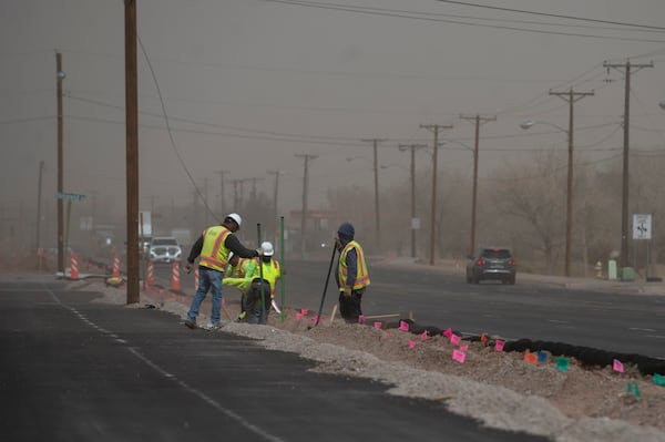 Construction workers work on a trench across as high winds and dust blow across 2nd Street NW in Albuquerque, N.M., Tuesday, March 18, 2025. (Jon Austria/The Albuquerque Journal via AP)