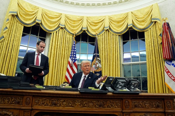 President Donald Trump signs executive orders in the Oval Office of the White House, Monday, Jan. 20, 2025, in Washington, as White House staff secretary Will Scharf watches. (AP Photo/Evan Vucci)