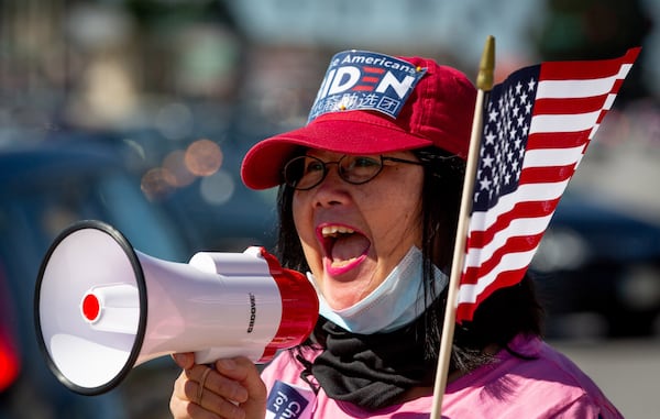 Asian Americans Democratic Club chairwoman Bilan Liao  leads a groop in chants during a Chinese for Biden sign-waving rally along Pleasant Hill Rd  Saturday, October 17, 2020 .  STEVE SCHAEFER / SPECIAL TO THE AJC 