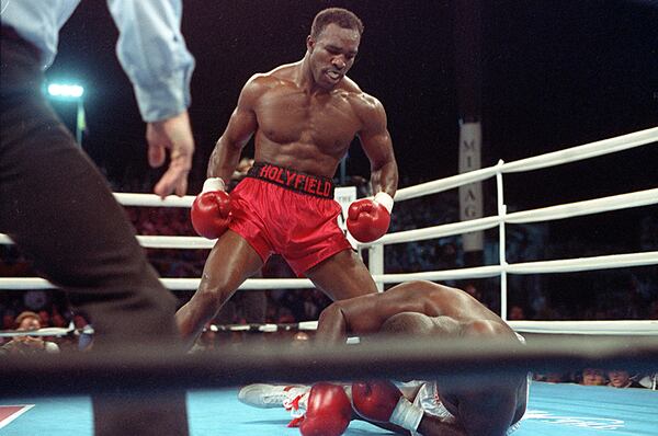 Evander Holyfield stands above the knocked-out James "Buster" Douglas  in the third round of their heavyweight title bout, on Oct. 25, 1990, at the Mirage Hotel in Las Vegas.