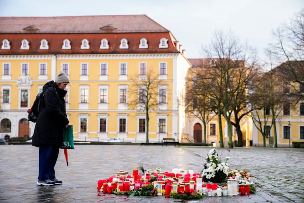 A woman stands next to flowers and candles laid down near the Magdeburg Cathedral, after a car drove into a crowd of a Christmas Mark on Friday evening, in Magdeburg, Germany, Sunday, Dec. 22, 2024. (AP Photo/Ebrahim Noroozi)