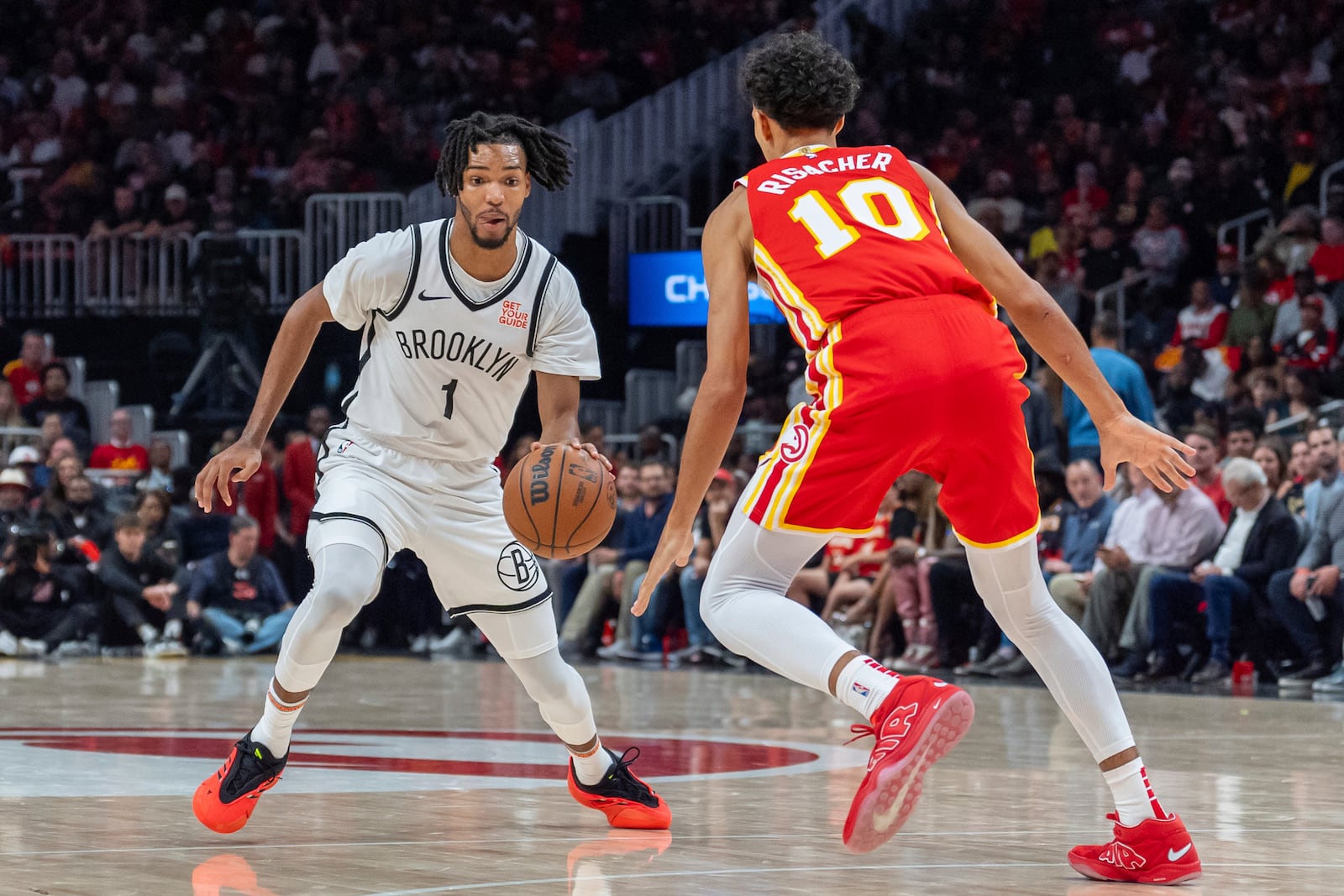 Brooklyn Nets forward Ziaire Williams (1) dribbles the ball while guarded by Atlanta Hawks forward Zaccharie Risacher (10) during the second half of an NBA basketball game, Wednesday, Oct. 23, 2024, in Atlanta. (AP Photo/Jason Allen)