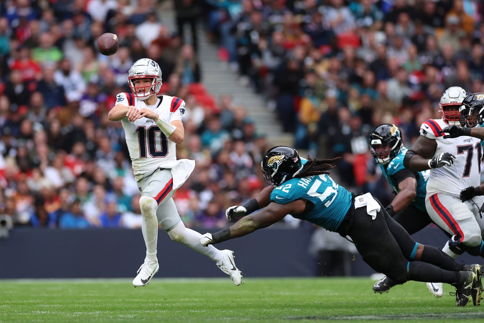 New England Patriots quarterback Drake Maye (10) is pressured by Jacksonville Jaguars defensive tackle DaVon Hamilton (52) during the first half of an NFL football game, Sunday, Oct. 20, 2024, in London. (AP Photo/Ian Walton)