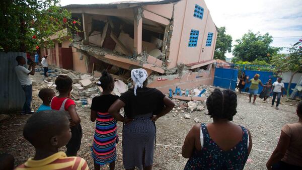 Residents stand looking at a collapsed school damaged bya magnitude 5.9 earthquake the night before, in Gros Morne, Haiti, Sunday, Oct. 7, 2018. Emergency teams worked to provide relief in Haiti on Sunday after the quake killed at least 11 people and left dozens injured. (AP Photo/Dieu Nalio Chery)