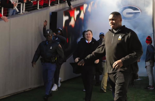 UGA football staff member Bryant Gantt leads the team onto the field at Sanford Stadium in Athens during a January 14 championship celebration. Gantt, the program's director of player support and operations, has job duties that include acting as the team's liaison to law enforcement. Gantt grew up in Athens and was a player who lettered on the team in 1989 and 1990. (Ryon Horne/Ryon.Horne@ajc.com)