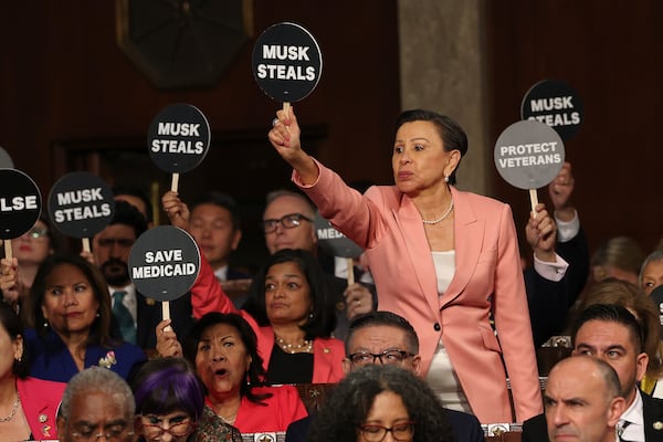 Rep. Nydia Velazquez, D-N.Y., holds a protest sign with fellow Democrats as President Donald Trump addresses a joint session of Congress at the Capitol in Washington, Tuesday, March 4, 2025. (Win McNamee/Pool Photo via AP)