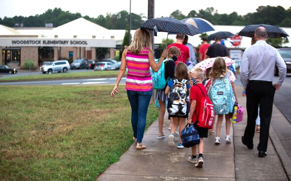 Parents walk their children to the entrance of Woodstock Elementary School on the first day of school on August 3, 2020.  STEVE SCHAEFER FOR THE ATLANTA JOURNAL-CONSTITUTION