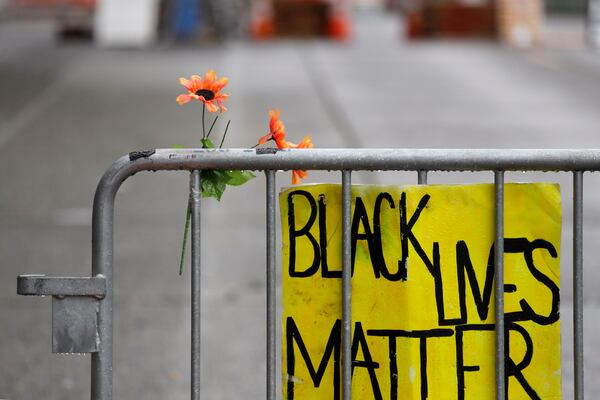 A barricade stands at the end of a street where a plywood-covered and closed Seattle police precinct stands Tuesday.