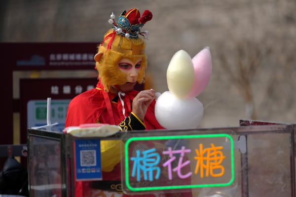 A vendor dressed with Monkey King costume sells cotton candy at the Chongwenmen Gate in Beijing, Sunday, March 9, 2025. (AP Photo/Andy Wong)