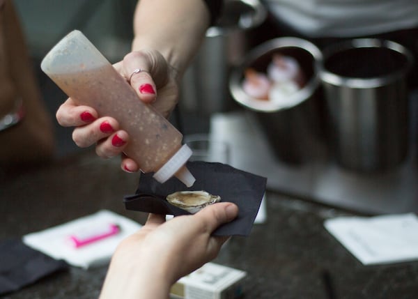 A server at Oysters Co in Atlanta hands over a freshly shucked oyster with hot sauce. PHOTO CREDIT: KayteeRuth Photography