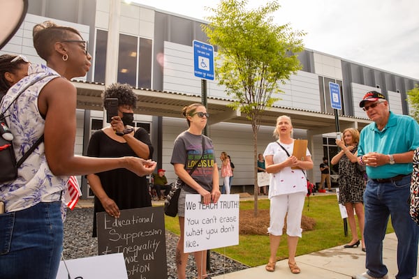 Before a Cobb County of Education board meeting begins, Dawn Mann, far left, debates with Leroy Emkin, far right.  Teachers, parents and local residents gather to voice their opinions on critical race theory and what Cobb County teaching and the reviews initiated by the school board Thursday, June 10, 2021.  (Jenni Girtman for The Atlanta Journal Constitution)