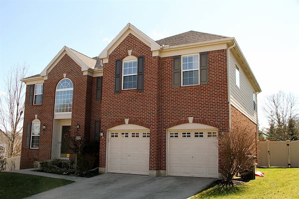 Keystone ornamentations accent the arched brick trim above garage doors and front windows of this brick 2-story home in Bellbrook. The rounded flower bed aside the walkway to the front door is mulched and planted with a dwarf tree, evergreens and bulbs that are already beginning to sprout. CONTRIBUTED PHOTOS BY KATHY TYLER