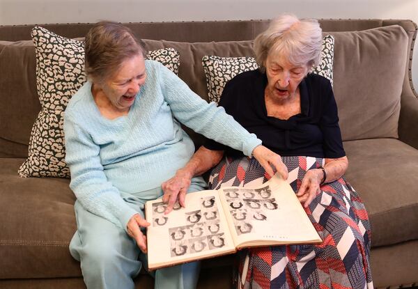 High school friends and now neighbors Elizabeth Carter (left) and Shirley Jones flip through the pages of their 1943 Girls High School yearbook. Curtis Compton / Curtis.Compton@ajc.com