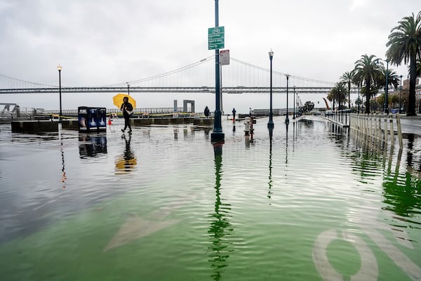 Water from the San Francisco Bay spills onto the Embarcadero as a result of high tides and storm-driven waves on Saturday, Dec. 14, 2024, in San Francisco. (AP Photo/Noah Berger)