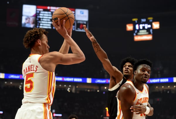 Atlanta Hawks guard Dyson Daniels, left, looks to shoot over Portland Trail Blazers guard Scoot Henderson, center, as Hawks center Clint Capela, right, defends during the first half of an NBA basketball game in Portland, Ore., Sunday, Nov. 17, 2024. (AP Photo/Steve Dykes)