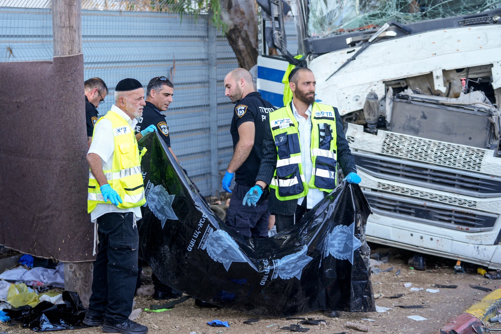 Israeli police and rescue services inspect the body of a truck driver that rammed into a bus stop near the headquarters of Israel's Mossad spy agency, wounding dozens of people, according to Israel's Magen David Adom rescue service in Tel Aviv, Israel, Sunday, Oct. 27, 2024. (AP Photo/Ohad Zwigenberg)