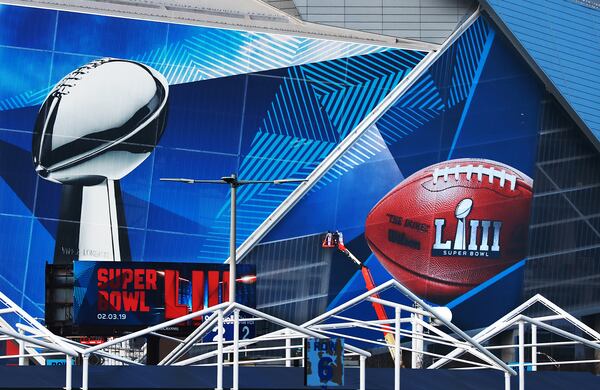 Workers use a lift to install a Super Bowl LIII wrap on the outside of Mercedes-Benz Stadium.