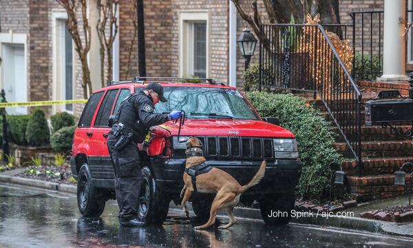 A Brookhaven police dog and his handler conduct a search of a Jeep Cherokee parked outside a home on Hedge Rose Court. Detectives searched the home for narcotics, according to police. JOHN SPINK / JSPINK@AJC.COM