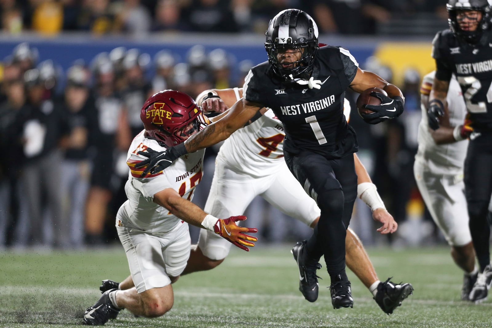 West Virginia running back Jahiem White (1) stiff arms Iowa State defensive back Beau Freyler (17) and rushes in for a touchdown during the first half of an NCAA college football game, Saturday, Oct. 12, 2024, in Morgantown, W.Va. (AP Photo/William Wotring)