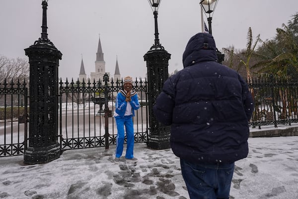 Gumbo Carlin, off New Orleans, takes a photo of his wife Tezrah Carlin in front of Jackson Square during a very rare snowstorm in New Orleans, Tuesday, Jan. 21, 2025. (AP Photo/Gerald Herbert)