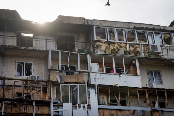 Residents clean up the damaged apartment in a multi-storey house after Russia's night drone attack, in Kyiv, Ukraine, Sunday, March 23, 2025. (AP Photo/Efrem Lukatsky)