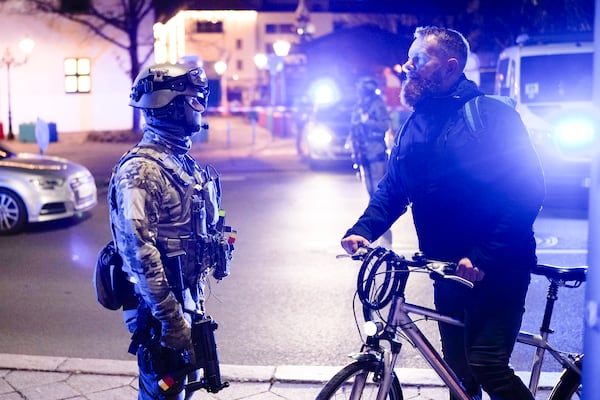 A police officer speaks with a man at a cordoned-off area near a Christmas Market after an incident in Magdeburg, Germany, Friday, Dec. 20, 2024. (AP Photo/Ebrahim Noroozi)