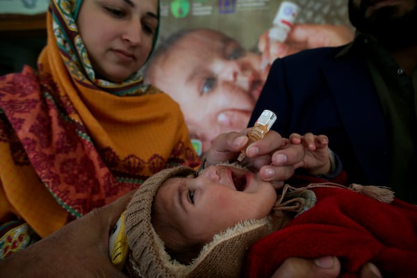 A health worker administers a polio vaccine to a child at a health center in Peshawar, Pakistan, Monday, Dec. 16, 2024. (AP Photo/Muhammad Sajjad)