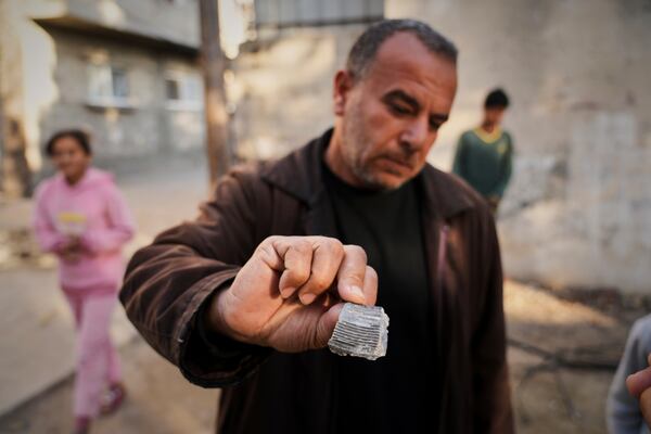 A man shows what he said was shrapnel from a projectile that struck a U.N. guesthouse, leaving one staff member dead and five others injured in Deir al-Balah, central Gaza, Wednesday, March 19, 2025. (AP Photo/Abdel Kareem Hana)